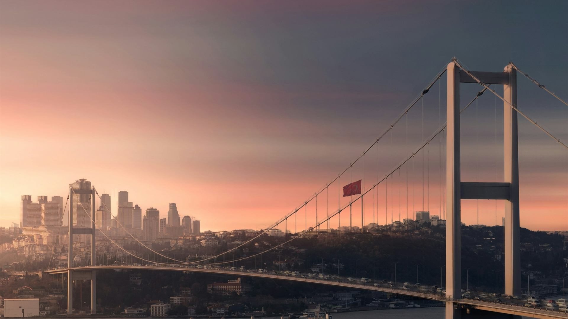 Bosphorus Bridge at sunset with a cargo ship passing through the strait in Istanbul