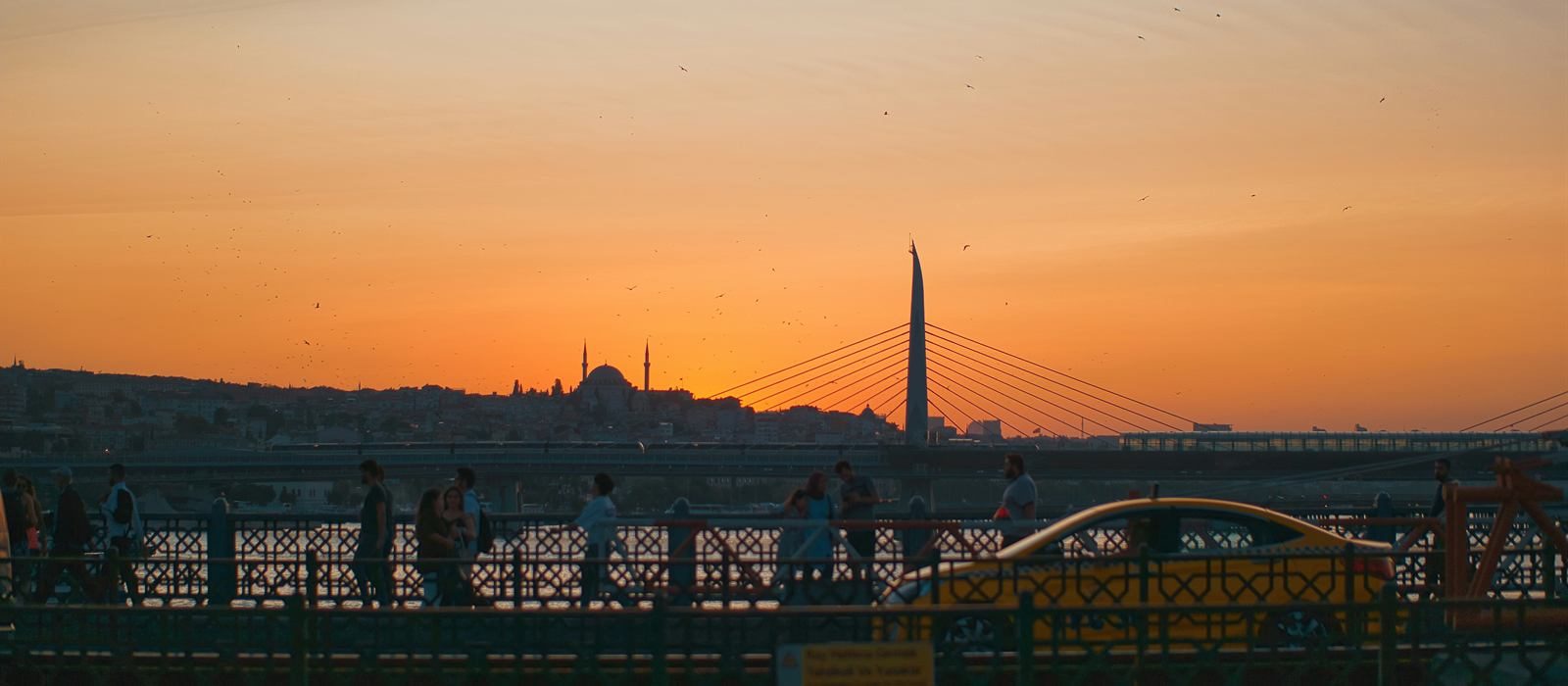 Galata Bridge at sunset with pedestrians and the Istanbul skyline