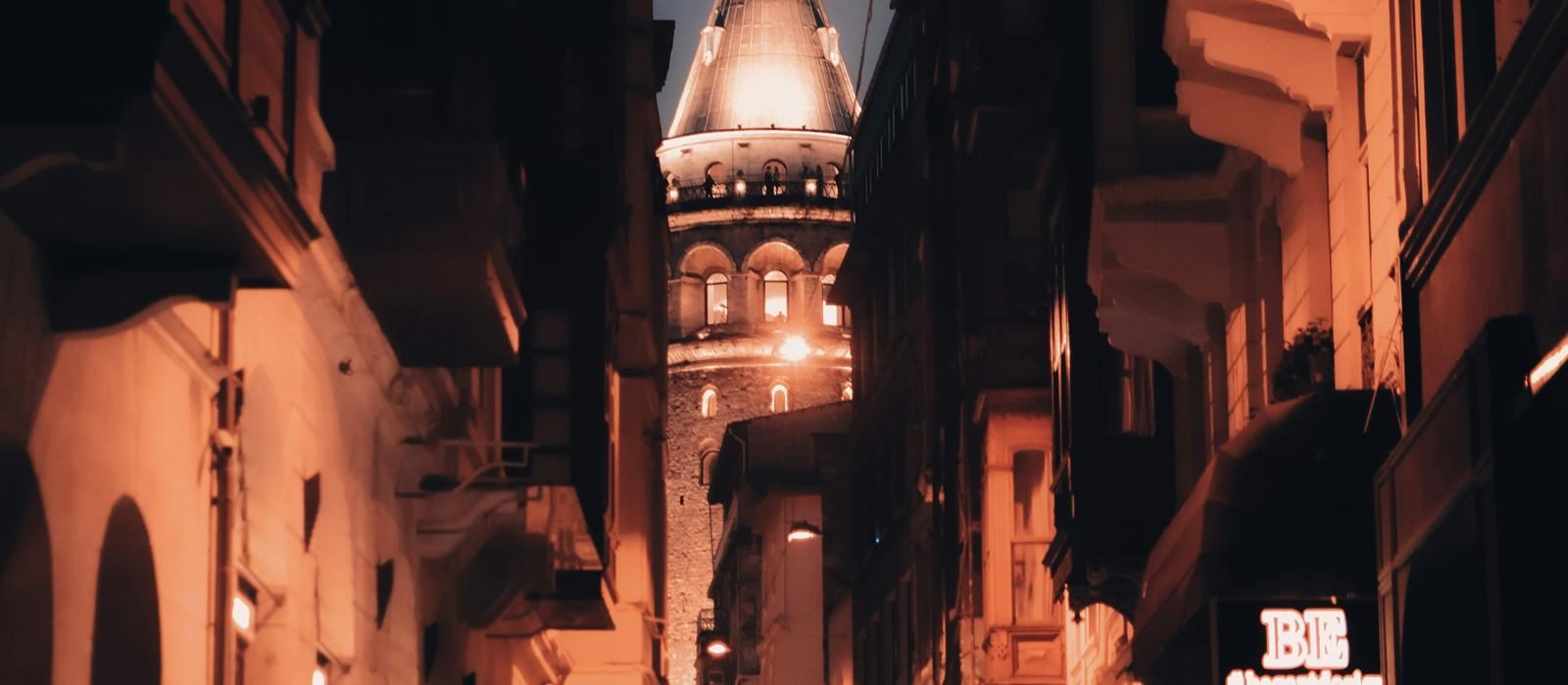Galata Tower seen from a lively Istanbul side street at night